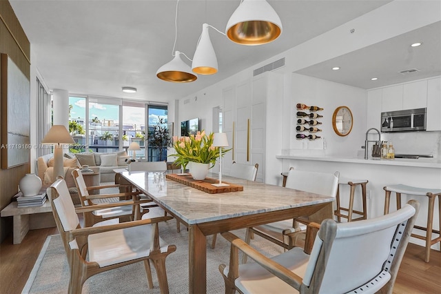 dining room with light hardwood / wood-style floors and a wall of windows