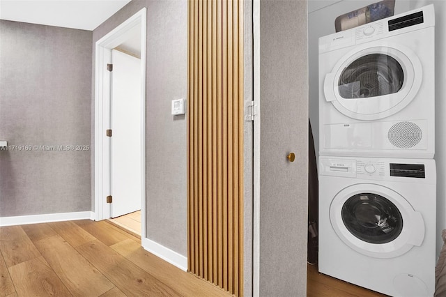 laundry room with hardwood / wood-style floors and stacked washer / dryer