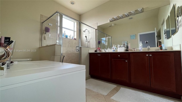 bathroom featuring a shower with door, vanity, washer / clothes dryer, tile patterned floors, and toilet