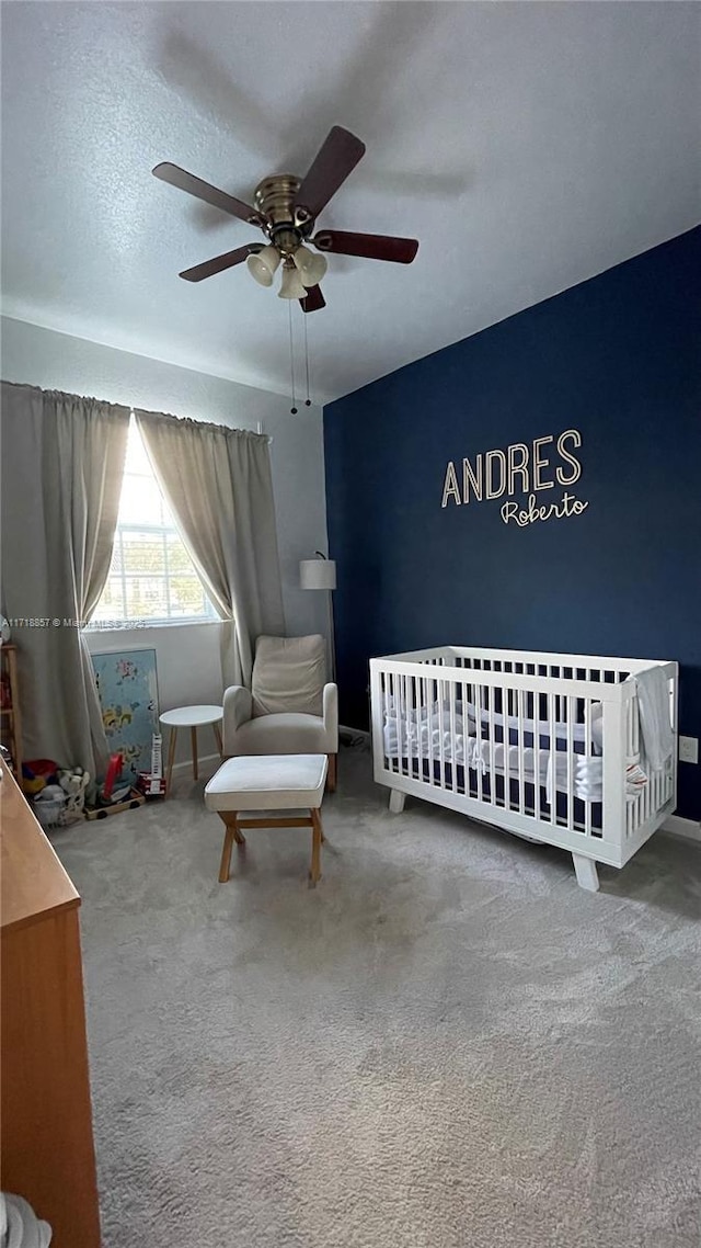 bedroom featuring carpet floors, a crib, and ceiling fan