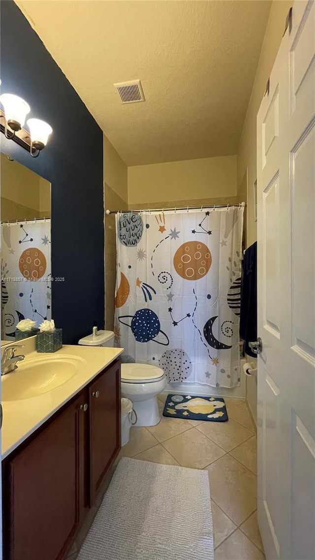 bathroom with tile patterned flooring, vanity, a textured ceiling, and toilet