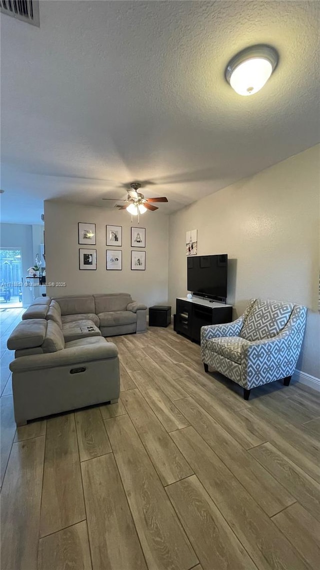 living room with hardwood / wood-style flooring, a textured ceiling, and ceiling fan