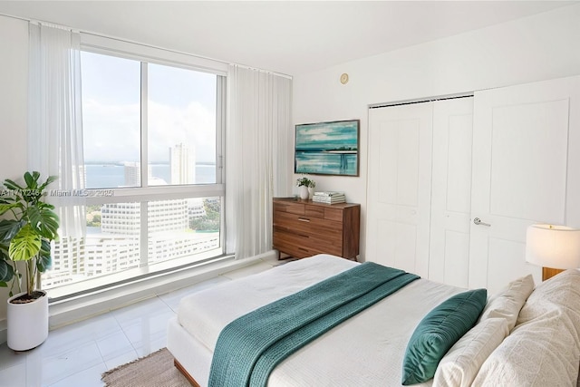 tiled bedroom with a closet, multiple windows, and a water view