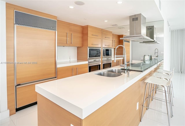 kitchen with built in appliances, sink, light tile patterned floors, and island exhaust hood