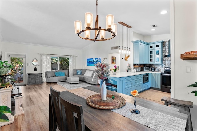 dining area featuring lofted ceiling, crown molding, an inviting chandelier, and light hardwood / wood-style floors