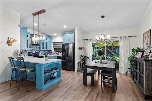 kitchen with a kitchen bar, blue cabinetry, decorative light fixtures, and stainless steel fridge with ice dispenser