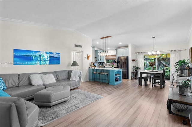 living room with vaulted ceiling, an inviting chandelier, crown molding, and light hardwood / wood-style flooring