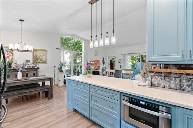 kitchen featuring lofted ceiling, pendant lighting, blue cabinetry, and a notable chandelier