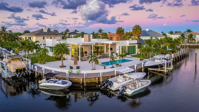 back house at dusk with a patio area and a water view