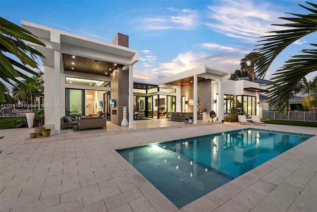 pool at dusk with an outdoor living space and a patio