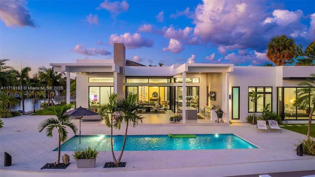 pool at dusk featuring a patio