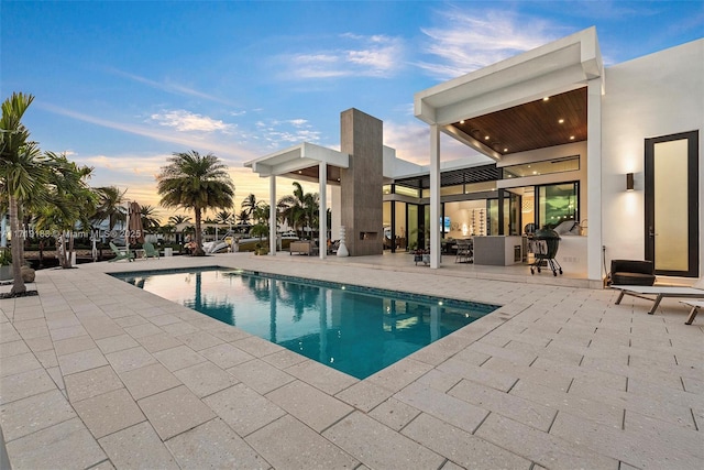 pool at dusk featuring a patio