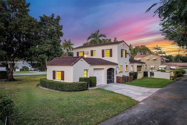 mediterranean / spanish-style house with a lawn and a garage