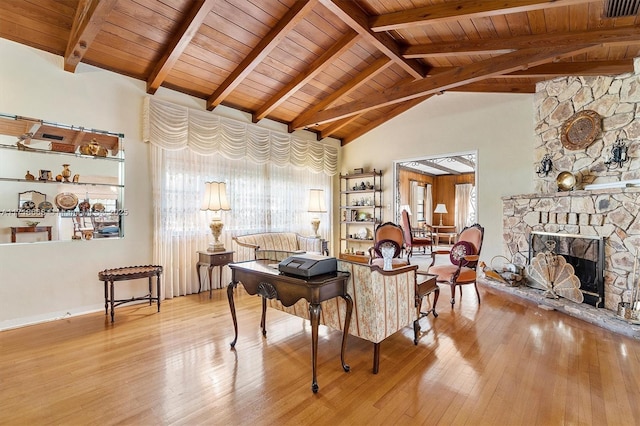 living room with beam ceiling, light wood-type flooring, and a fireplace