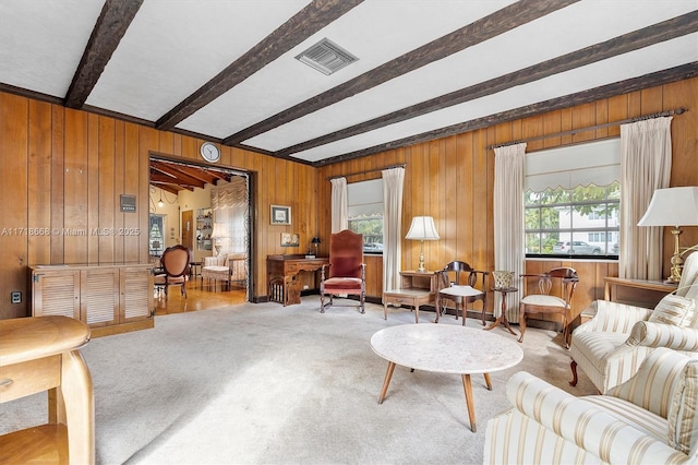 carpeted living room with wood walls, a healthy amount of sunlight, and beam ceiling