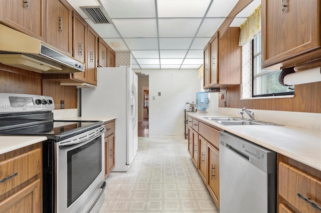 kitchen with appliances with stainless steel finishes, a paneled ceiling, and sink