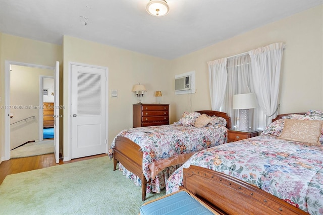 bedroom with light hardwood / wood-style floors and an AC wall unit