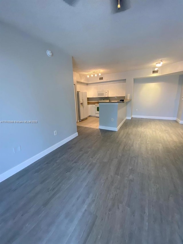 unfurnished living room featuring dark hardwood / wood-style flooring and track lighting