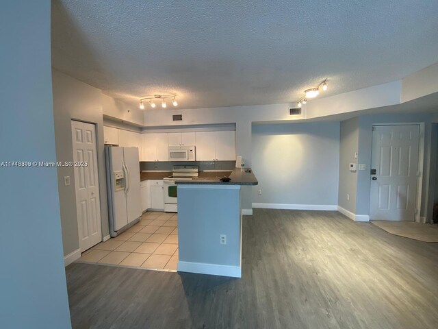 kitchen featuring a textured ceiling, white cabinetry, light tile patterned floors, and white appliances