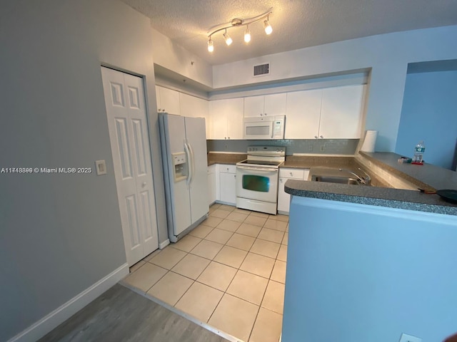 kitchen featuring white appliances, sink, a textured ceiling, white cabinetry, and kitchen peninsula