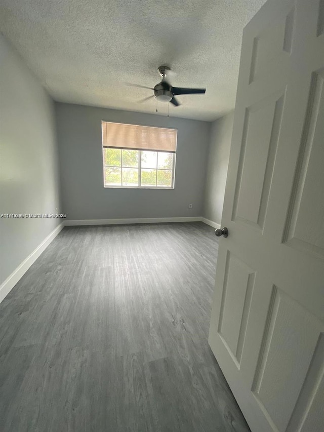 unfurnished room with ceiling fan, hardwood / wood-style floors, and a textured ceiling