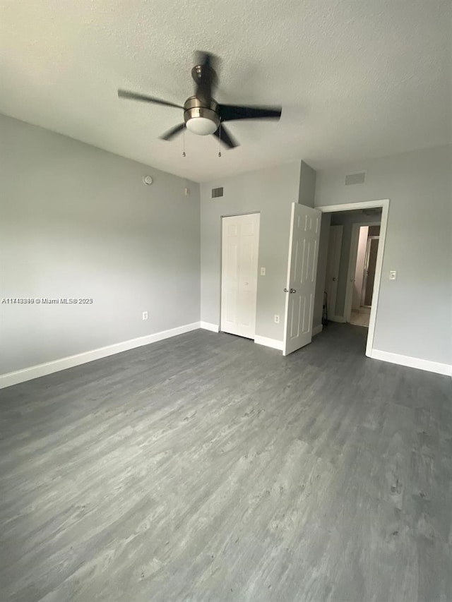 unfurnished bedroom with dark hardwood / wood-style flooring, a textured ceiling, a closet, and ceiling fan