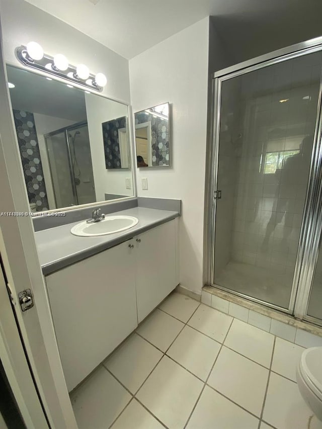 bathroom with toilet, vanity, tile patterned floors, and an enclosed shower