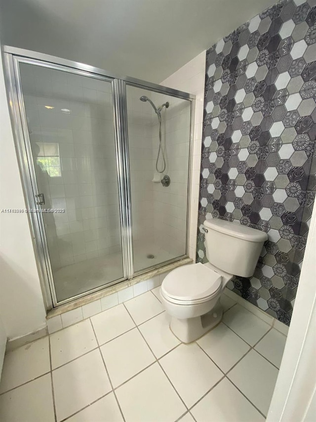 bathroom with toilet, tile patterned floors, tile walls, and a shower with shower door