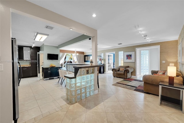 kitchen with a breakfast bar, stainless steel fridge, light tile patterned floors, a notable chandelier, and kitchen peninsula