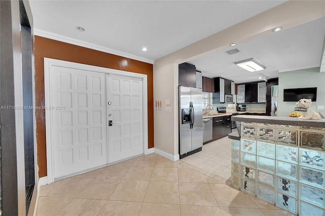 kitchen with appliances with stainless steel finishes, ornamental molding, dark brown cabinetry, sink, and light tile patterned floors