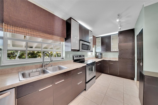 kitchen featuring rail lighting, sink, dark brown cabinets, light tile patterned flooring, and stainless steel appliances