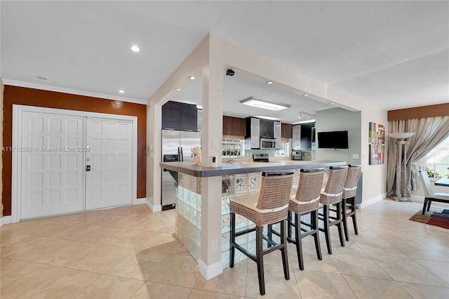 kitchen with a breakfast bar, light tile patterned flooring, kitchen peninsula, and appliances with stainless steel finishes