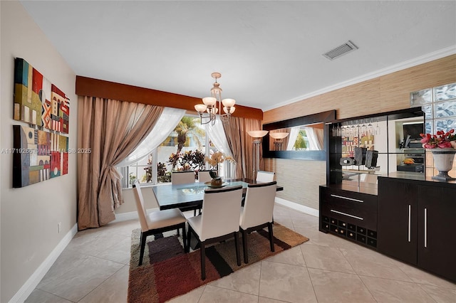 tiled dining room featuring ornamental molding and an inviting chandelier