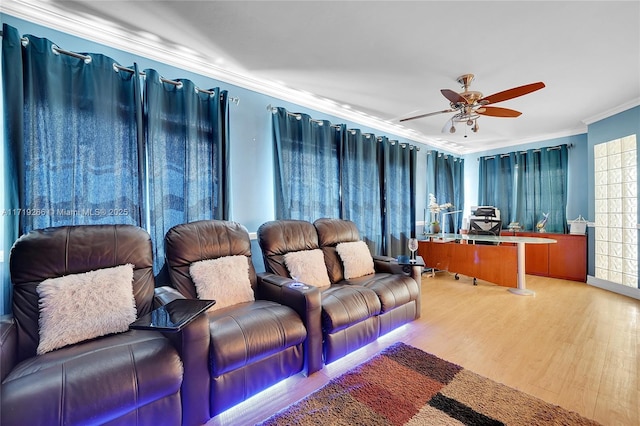 cinema with ceiling fan, ornamental molding, and light wood-type flooring