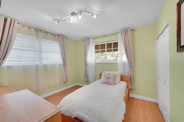 bedroom featuring light wood-type flooring, rail lighting, and a closet