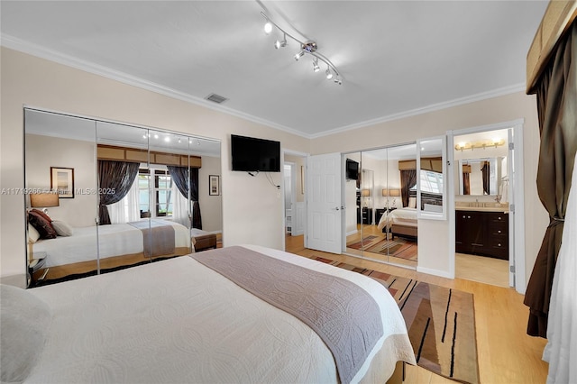 bedroom with connected bathroom, sink, light hardwood / wood-style flooring, a closet, and ornamental molding