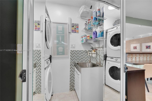 laundry area featuring sink, light tile patterned floors, and stacked washer / drying machine