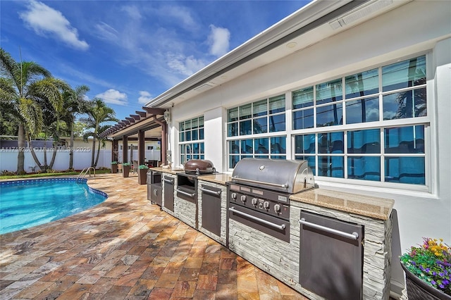 view of swimming pool featuring grilling area, a patio, and an outdoor kitchen