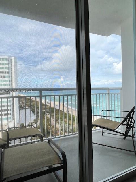 balcony with a water view and a view of the beach