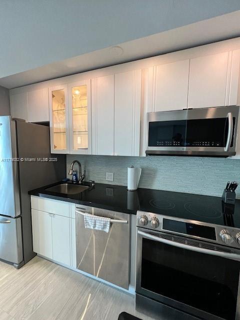 kitchen with backsplash, sink, white cabinets, and stainless steel appliances