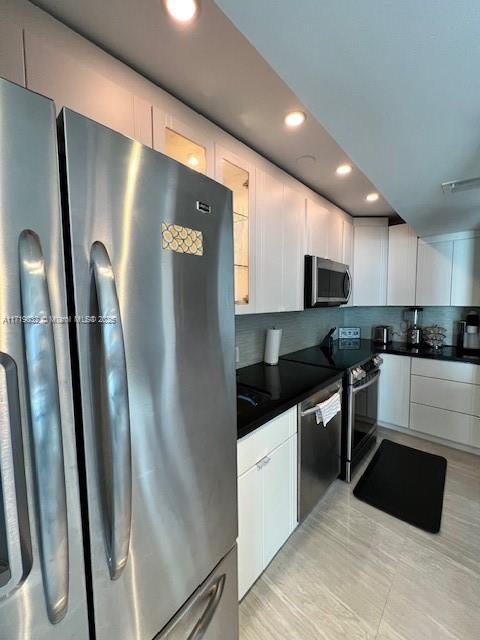 kitchen with tasteful backsplash, white cabinetry, and appliances with stainless steel finishes