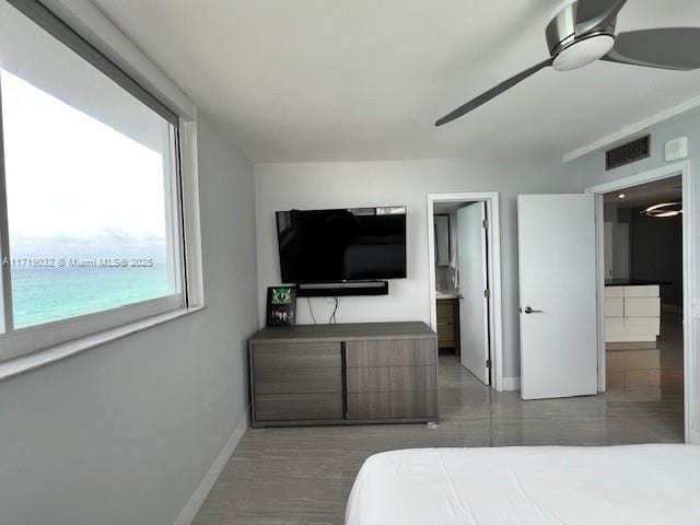 bedroom featuring a water view, ensuite bath, and ceiling fan