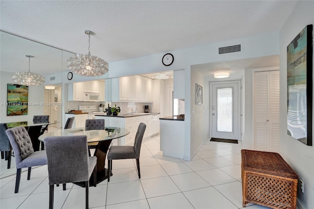 dining room featuring light tile patterned floors, a textured ceiling, a chandelier, and visible vents
