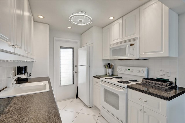 kitchen with white cabinets, dark countertops, a sink, white appliances, and decorative backsplash