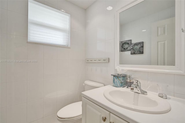 bathroom featuring tile walls, vanity, and toilet