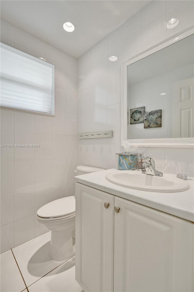 bathroom with vanity, toilet, and tile walls
