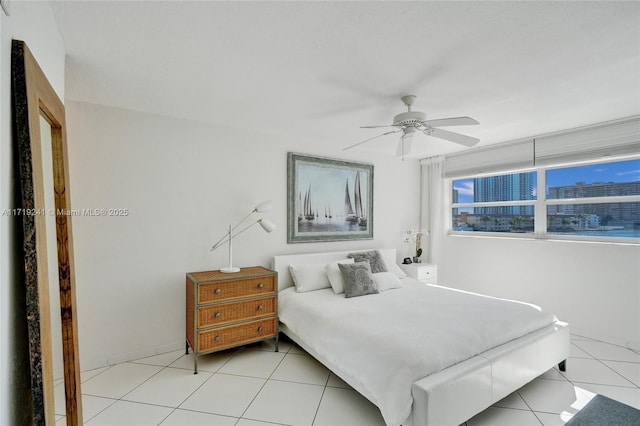 bedroom featuring light tile patterned flooring, a ceiling fan, and baseboards