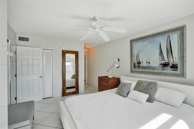bedroom with a ceiling fan, visible vents, light tile patterned floors, and a closet