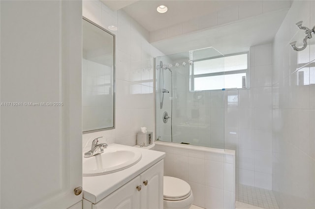 full bath featuring toilet, tile walls, a tile shower, and vanity