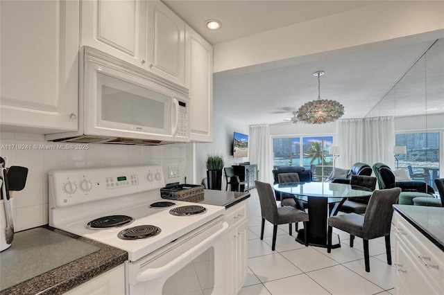 kitchen with light tile patterned flooring, dark countertops, white appliances, open floor plan, and backsplash